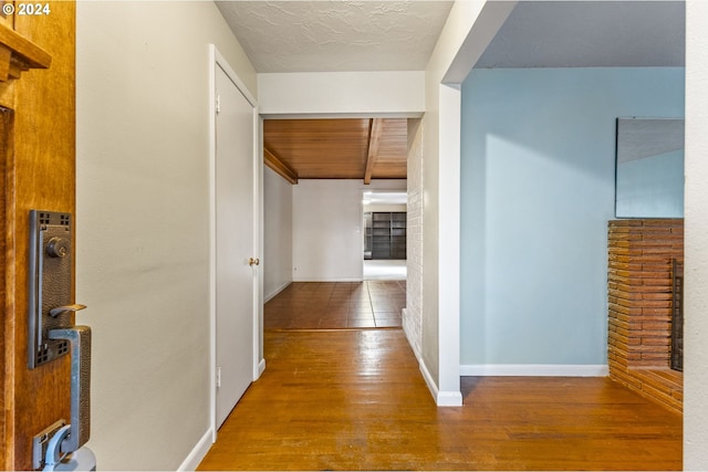 hallway featuring beamed ceiling, hardwood / wood-style floors, and wooden ceiling