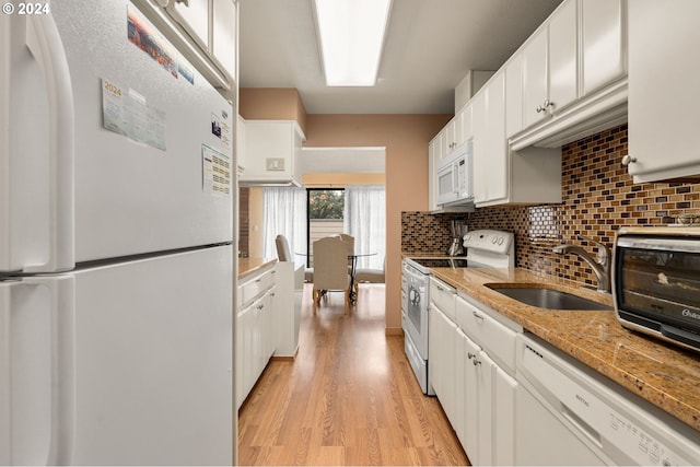 kitchen with white cabinetry, light stone countertops, light hardwood / wood-style floors, sink, and white appliances