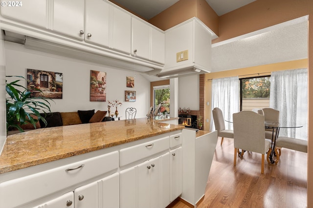 kitchen featuring light hardwood / wood-style flooring, white cabinetry, and light stone counters