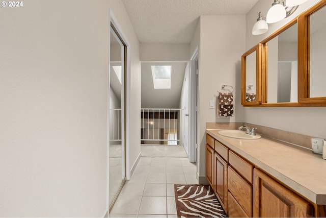 bathroom with vanity, a textured ceiling, a skylight, and tile patterned flooring