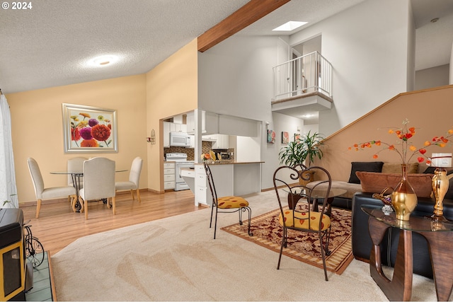 living room with beam ceiling, light wood-type flooring, a textured ceiling, high vaulted ceiling, and a skylight