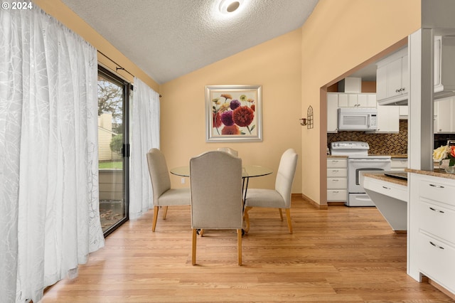 dining room featuring a textured ceiling, light wood-type flooring, and vaulted ceiling