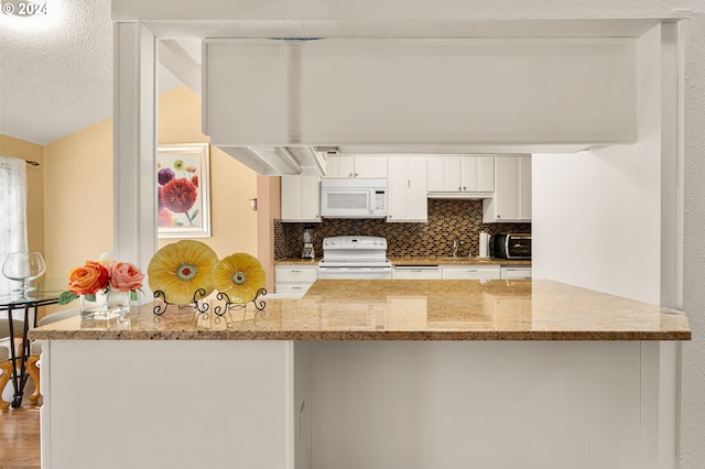 kitchen with hardwood / wood-style floors, light stone countertops, white cabinetry, white appliances, and tasteful backsplash