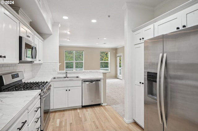 kitchen with stainless steel appliances, crown molding, sink, white cabinets, and light hardwood / wood-style floors