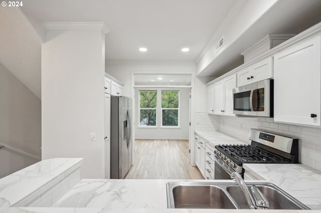 kitchen with light stone counters, appliances with stainless steel finishes, decorative backsplash, white cabinets, and ornamental molding