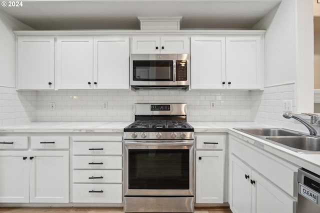 kitchen with white cabinets, backsplash, sink, and stainless steel appliances