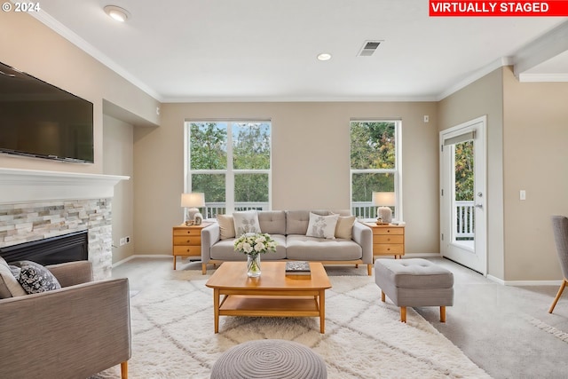 living room featuring light carpet, a fireplace, a healthy amount of sunlight, and ornamental molding