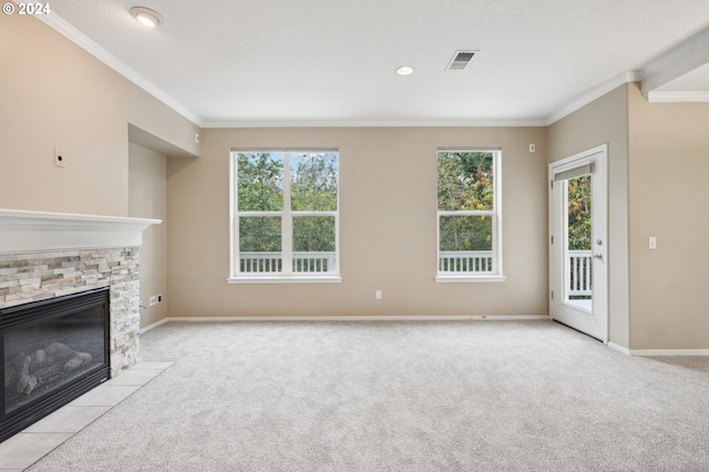 unfurnished living room featuring a healthy amount of sunlight, ornamental molding, a fireplace, and light carpet