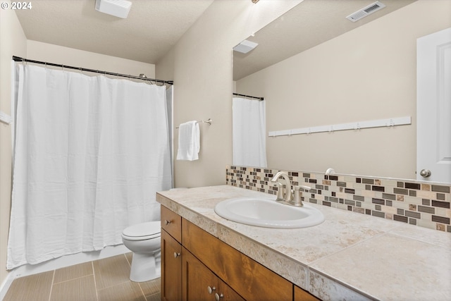 bathroom featuring vanity, toilet, a textured ceiling, and tasteful backsplash