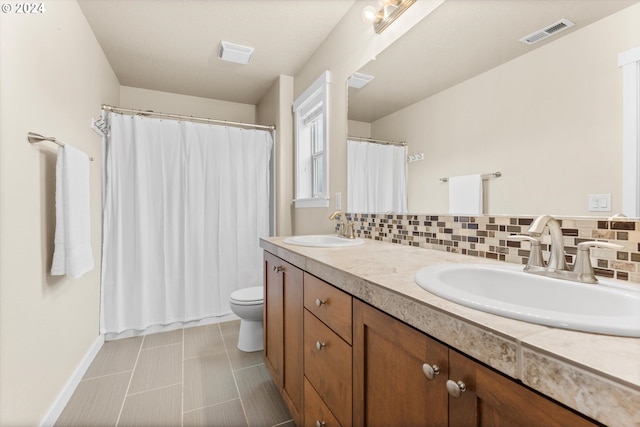 bathroom with vanity, toilet, and tasteful backsplash