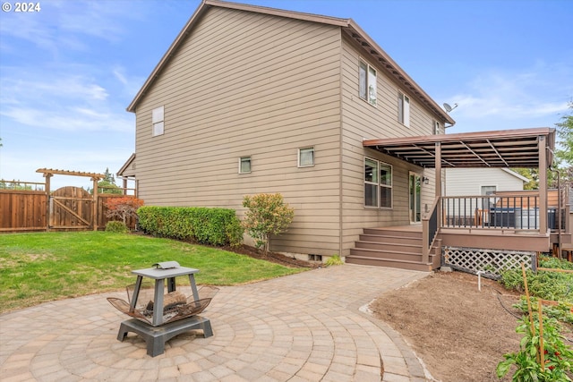 rear view of property featuring a deck, a patio, and a yard