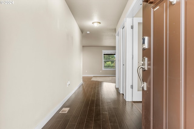 corridor with a textured ceiling and dark wood-type flooring