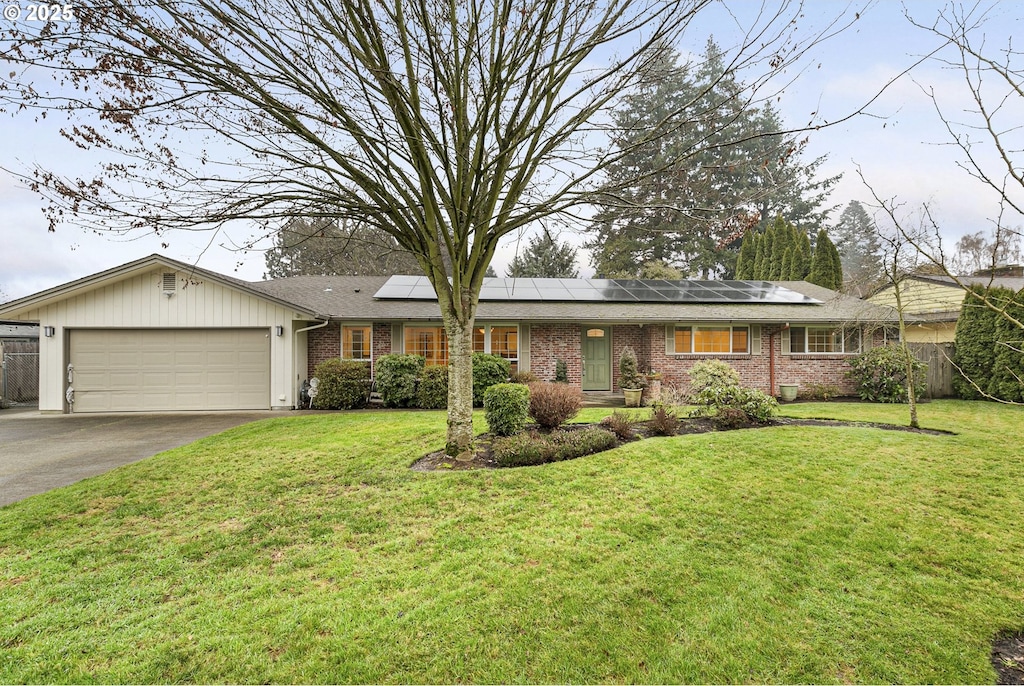 ranch-style home with a front lawn, a garage, and solar panels