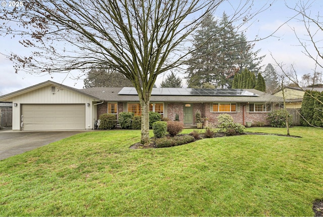 ranch-style home with a front lawn, a garage, and solar panels