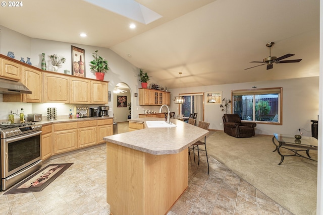 kitchen with lofted ceiling with skylight, light carpet, a center island with sink, sink, and high end stainless steel range oven