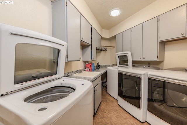 laundry area with washer and dryer, light parquet floors, cabinets, and sink