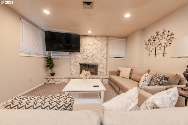 carpeted living room with a stone fireplace