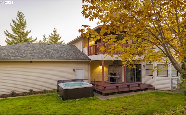 rear view of house with a wooden deck, a hot tub, and a yard