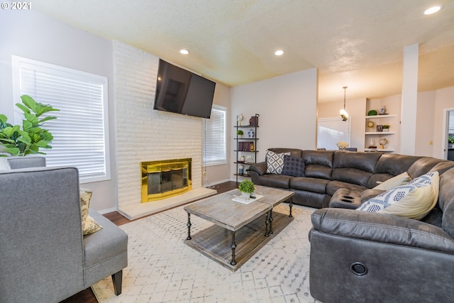 living room with a brick fireplace, a healthy amount of sunlight, and light hardwood / wood-style flooring