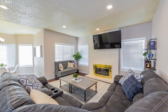 living room featuring brick wall, light wood-type flooring, a textured ceiling, and a fireplace