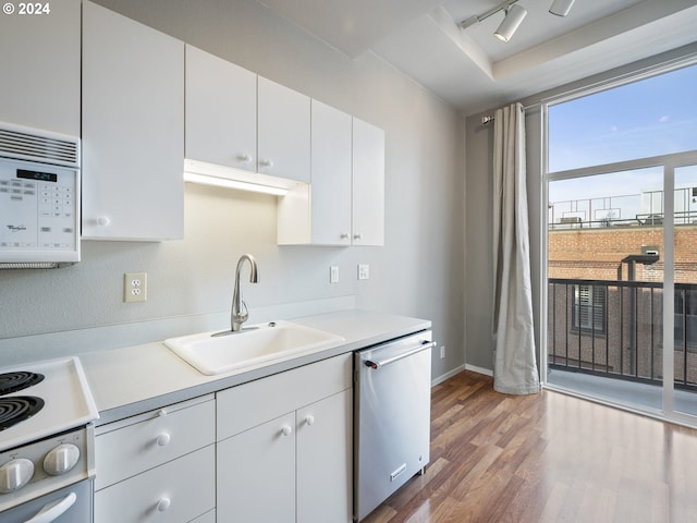 kitchen with stainless steel dishwasher, sink, hardwood / wood-style flooring, range, and white cabinetry