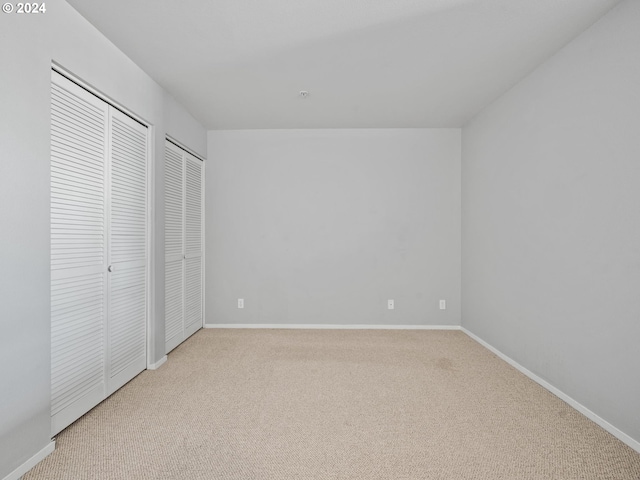 unfurnished bedroom with light carpet and multiple closets