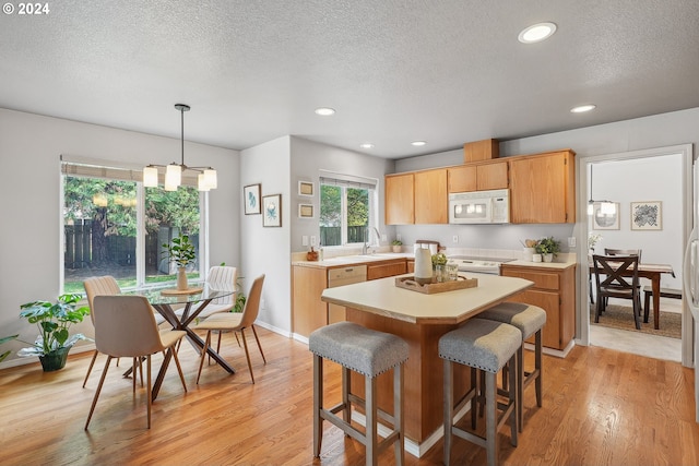 kitchen with hanging light fixtures, white appliances, a notable chandelier, and light wood-type flooring