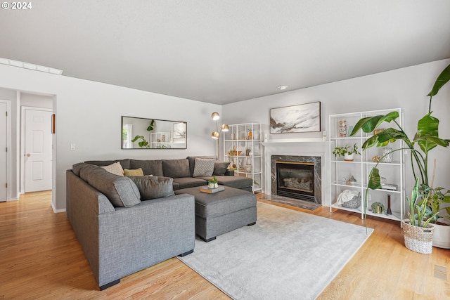 living room with a high end fireplace and wood-type flooring