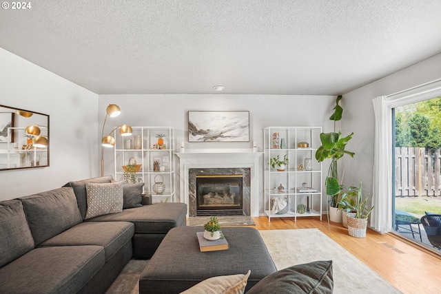 living room with hardwood / wood-style floors, a high end fireplace, and a textured ceiling