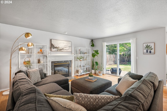 living room featuring light hardwood / wood-style flooring, a textured ceiling, and a premium fireplace