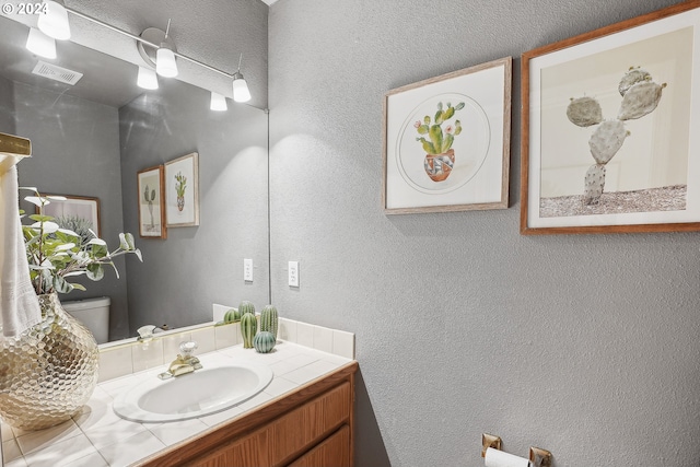 bathroom with a textured ceiling, toilet, and vanity