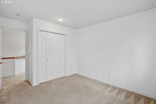 unfurnished bedroom with a closet and light colored carpet