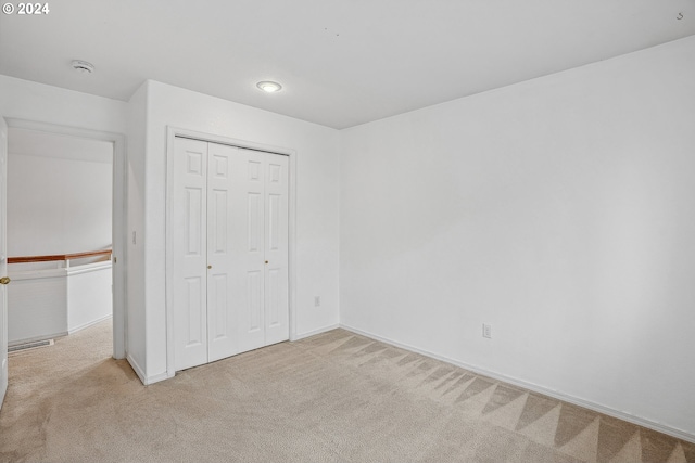 unfurnished bedroom featuring a closet and light carpet