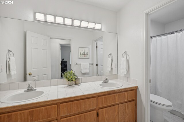 bathroom featuring toilet, dual bowl vanity, and tile patterned flooring