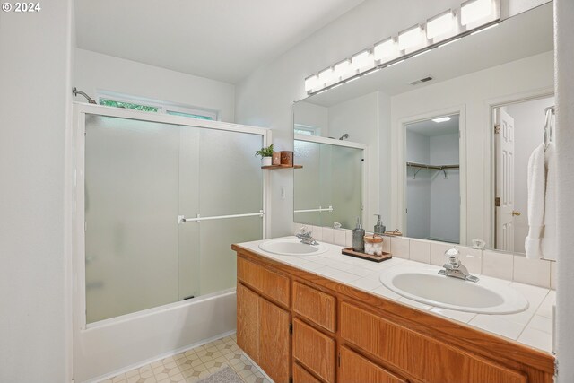 bathroom with double sink vanity, combined bath / shower with glass door, and tile patterned floors