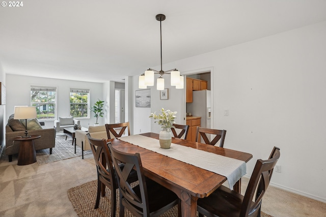 dining space with a chandelier and light carpet