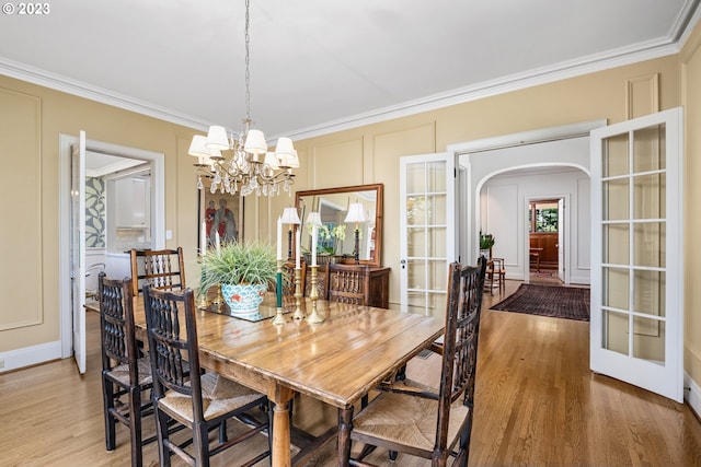 dining area with ornamental molding, hardwood / wood-style floors, and a notable chandelier