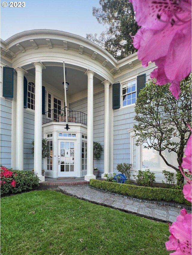 property entrance with a balcony, french doors, and a lawn