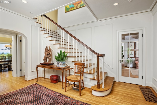 stairway with ornamental molding and hardwood / wood-style floors