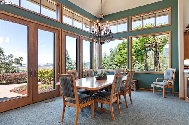 dining area featuring carpet, a high ceiling, a chandelier, and a healthy amount of sunlight