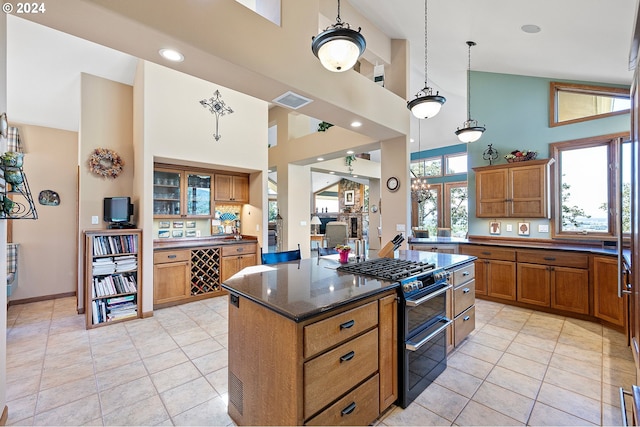 kitchen featuring light tile patterned flooring, a towering ceiling, decorative light fixtures, range with two ovens, and a kitchen island