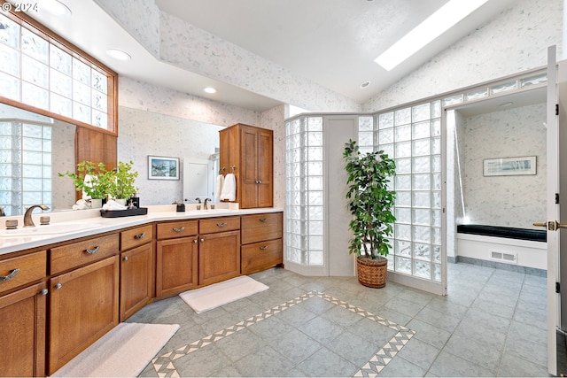 bathroom with vaulted ceiling with skylight, vanity, and tile patterned floors