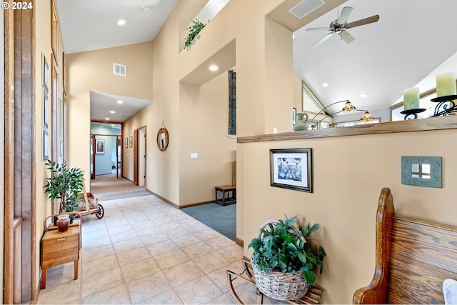 hallway featuring light tile patterned floors and high vaulted ceiling