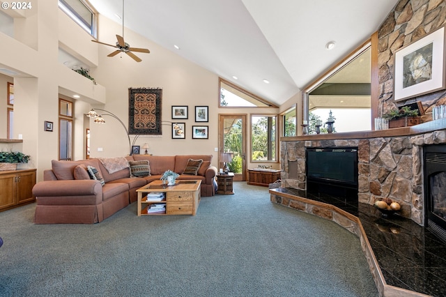 carpeted living room featuring a towering ceiling, a stone fireplace, and ceiling fan