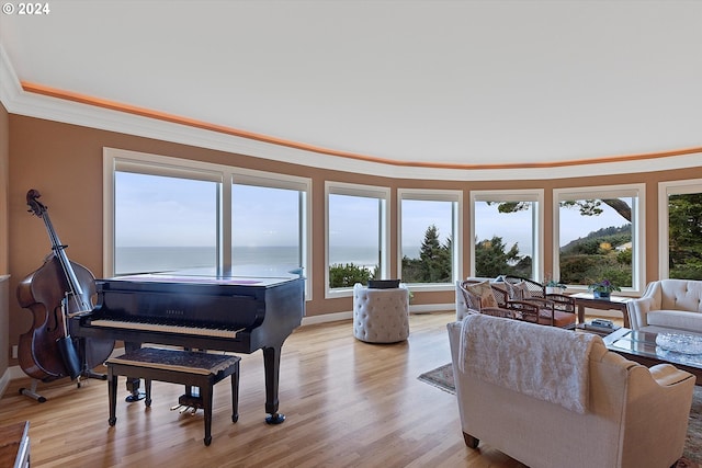 living room featuring a water view, light wood-type flooring, crown molding, and a wealth of natural light