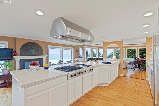 kitchen featuring stainless steel gas stovetop, light wood-type flooring, tile counters, white cabinetry, and extractor fan