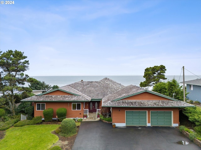 ranch-style home featuring a garage, a water view, and a front lawn