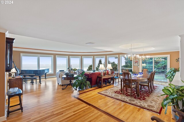 dining space with light hardwood / wood-style floors, a water view, crown molding, and a chandelier