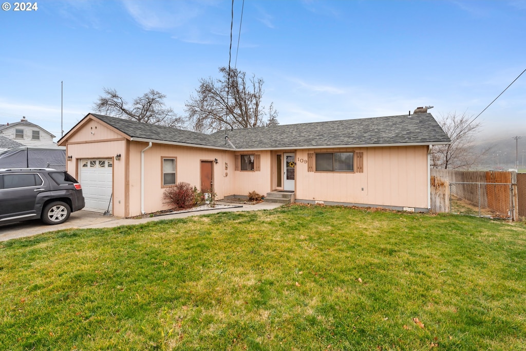 ranch-style house featuring a garage and a front lawn