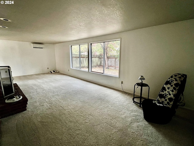 sitting room with a textured ceiling, carpet flooring, and a wall mounted air conditioner